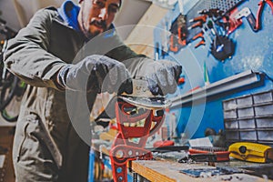 A male worker in a ski service workshop repairs the sliding surface of the skis. Close-up of a hand with a plastic scrapper for