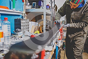 A male worker in a ski service workshop repairs the sliding surface of the skis. Close-up of a hand with a plastic scrapper for