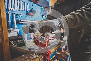 A male worker in a ski service workshop repairs the sliding surface of the skis. Close-up of a hand with a plastic scrapper for