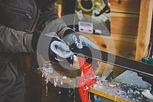 A male worker in a ski service workshop repairs the sliding surface of the skis. Close-up of a hand with a plastic scrapper for re