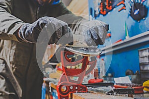 A male worker in a ski service workshop repairs the sliding surface of the skis. Close-up of a hand with a plastic scrapper for re