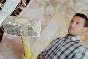 Male worker smashing wall