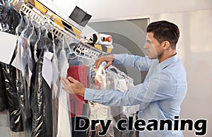 Male worker taking clothes from conveyor at dry-cleaner`s