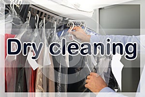 Male worker taking clothes from garment conveyor at dry-cleaner`s