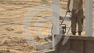 A male worker tamps sand during the construction of a road for laying tiles. Soil clotting equipment, construction