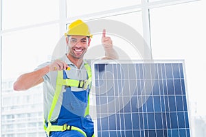 Male worker tightening solar panel while gesturing thumbs up