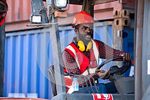 Male worker in uniform and helmet driving and operating on diesel container forklift truck at commercial dock site