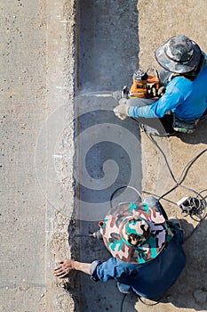 Male worker is using a drilling tool to drill into a concrete road to reinforce the anchor before building a stable parallel