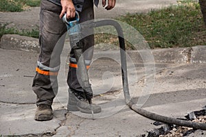 Male worker using jackhammer pneumatic drill machinery on road repair