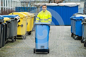 Male Worker Walking With Dustbin On Street