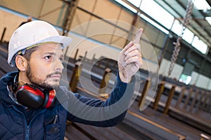 male worker in warehouse pointing upwards