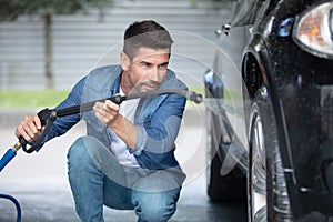 male worker wash car with high pressure washer