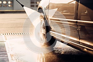 Male worker wash the car with high pressure washer