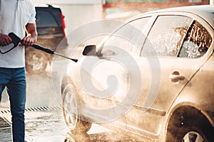 Male worker wash the car with high pressure washer