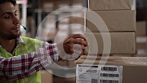Male worker wear headset carries boxes inside warehouse