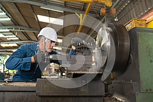 Male worker working on a lathe machine in metal industry factory on a business day