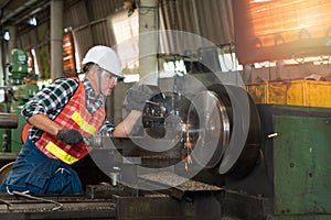 Male worker working on a lathe machine in metal industry factory on a business day