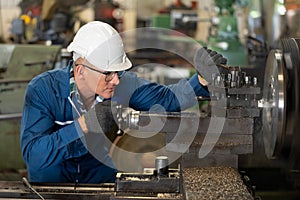 Male worker working on a lathe machine in metal industry factory on a business day