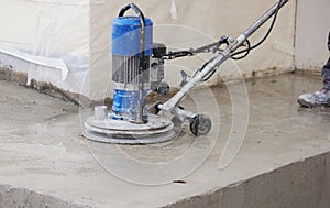 male worker works with the diamond grinding machine, polishing the porch in front of the office building. the cement floor and co