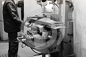 A male worker works on a larger metal iron locksmith lathe, equipment for repairs, metal work in a workshop at a metallurgical