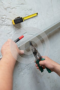 Male worker works with profile for drywall, cuts it with metal shears. Construction work, repair. photo