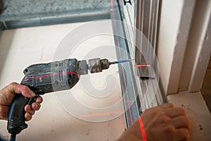 Male worker works with profile for drywall, setting, assembling with drill. Construction work, repair.