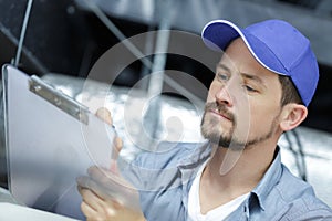 Male worker writing on clipboard