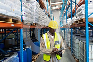 Male worker writing on clipboard in warehouse