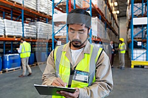 Male worker writing on clipboard in warehouse