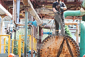 Male workers assemblers mount a shell-and-tube heat exchanger, repair equipment at an oil refining petrochemical chemical