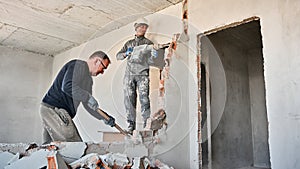 Male workers breaking wall in apartment under renovation.