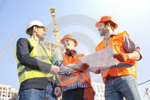 Male workers engineers at construction site in helmets hardhats. Construction manager meeting handshake.