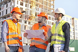 Construction site with workers in helmets hardhats near high-rise building skyscraper