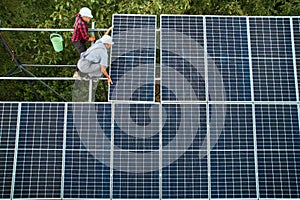Male workers installing solar panel system outdoors.