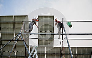 Male workers installing solar panels on metal construction.