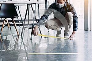 Male workers preparing masking tape to symbolize social distances