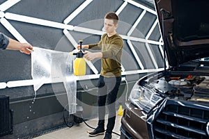 Male workers wets template of car protection film