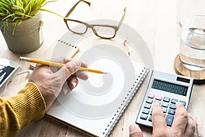 Male working with calculator and notepad on worktable.