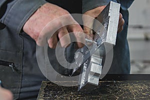 Male working hands grinds the metal detail with a scraper