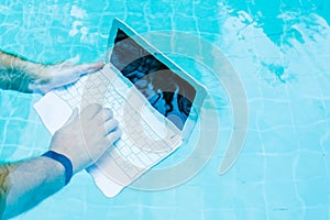 Male works on minicomputer under water. Minicomputer at the bottom of the pool. The concept of a lot of work at work