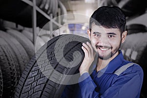 Male workshop worker carrying a tire