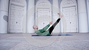 Male yoga instructor performs indoor exercise with lots of doors Ardha navasana