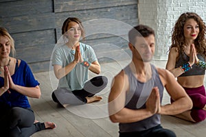 Male yoga instructor taking yoga class in fitness studio