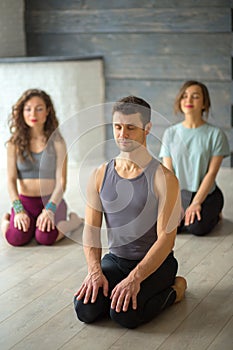 Male yoga instructor taking yoga class in fitness studio