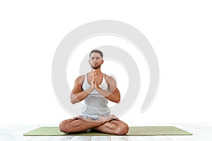 Male yoga maditates in classical pose in studio over white background