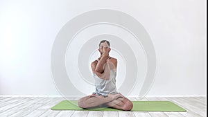 Male yoga meditates in classical pose in studio over white background