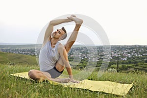 Male yoga in nature. Handsome man stretching his leg during yoga workout in mountains.