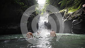 Males and female tourist bathing in the waterfalls and enjoying the fresh water.