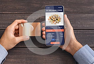 Males hands hold credit card to pay for order online and delivery food. And smartphone with application