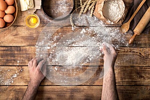 Males hands sprinkle with flour wooden table for making dough